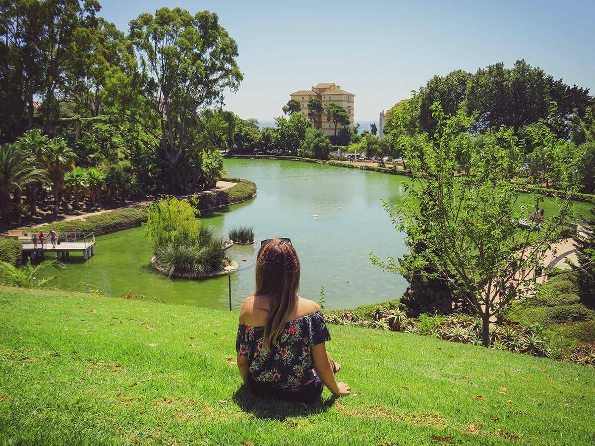 18+ Fun Things To Do In Benalmadena By a Local 3 Cristina sat on the grass looking the artificial lake in La Paloma Park in Benalmadena, Spain.