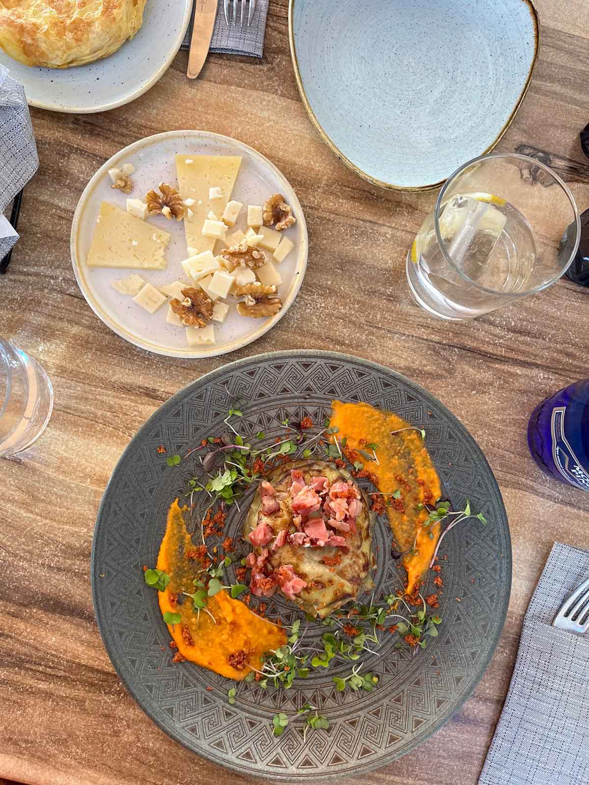 Grilled artichoke with salmorejo soup and a plate of manchego cheese with nuts.