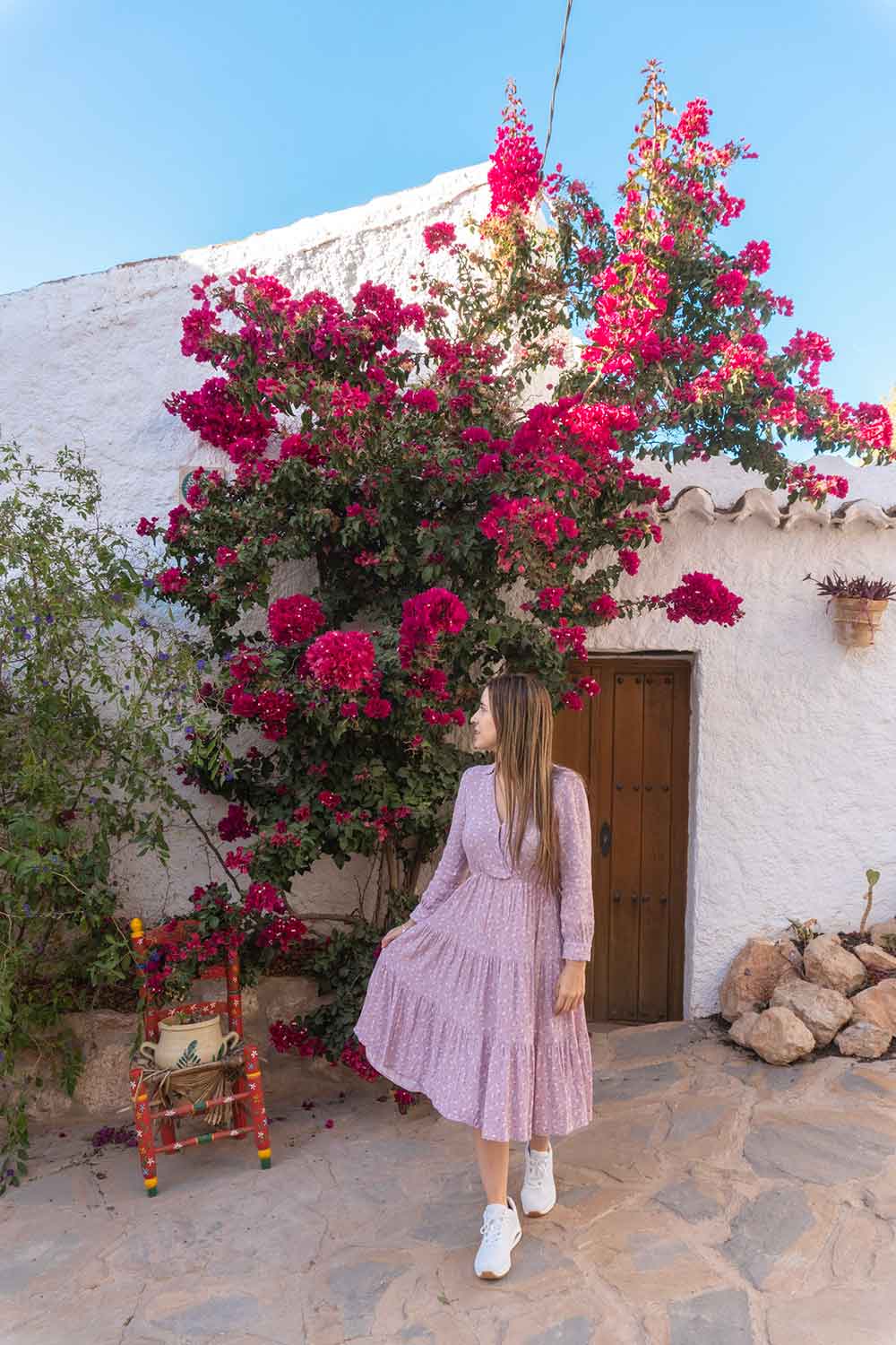 a photo of a woman holding her dress in a pretty whitewashed street