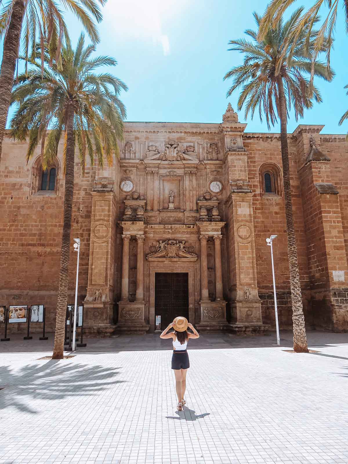 Woman posing in front of Almeria Cathedral on a sunny day.