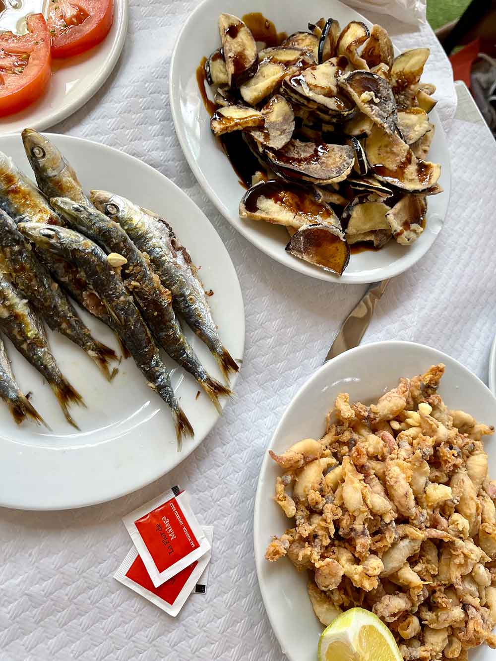 A plate of grilled sardines, fried squid and aubergines with sugar cane honey.