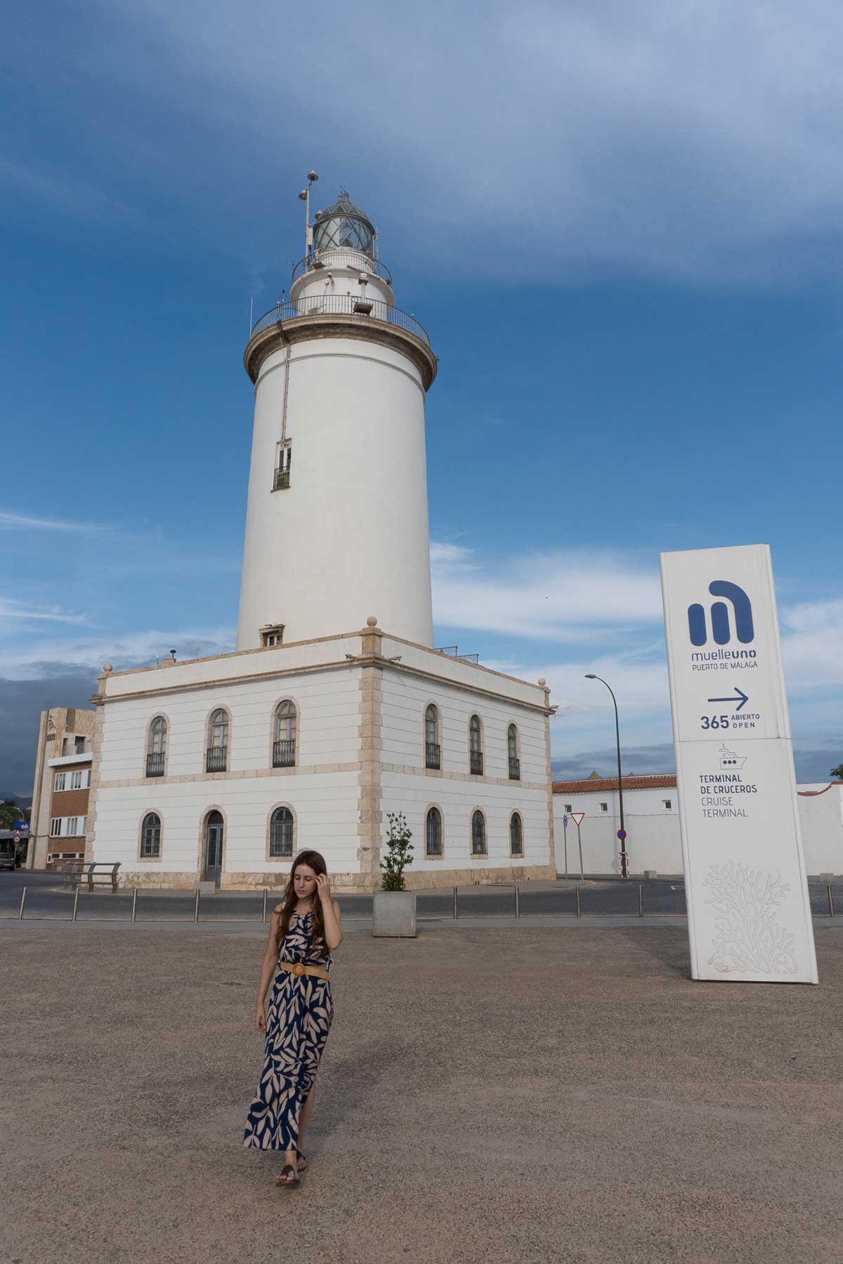 Woman posing in front of the lighthouse in Malaga's port.