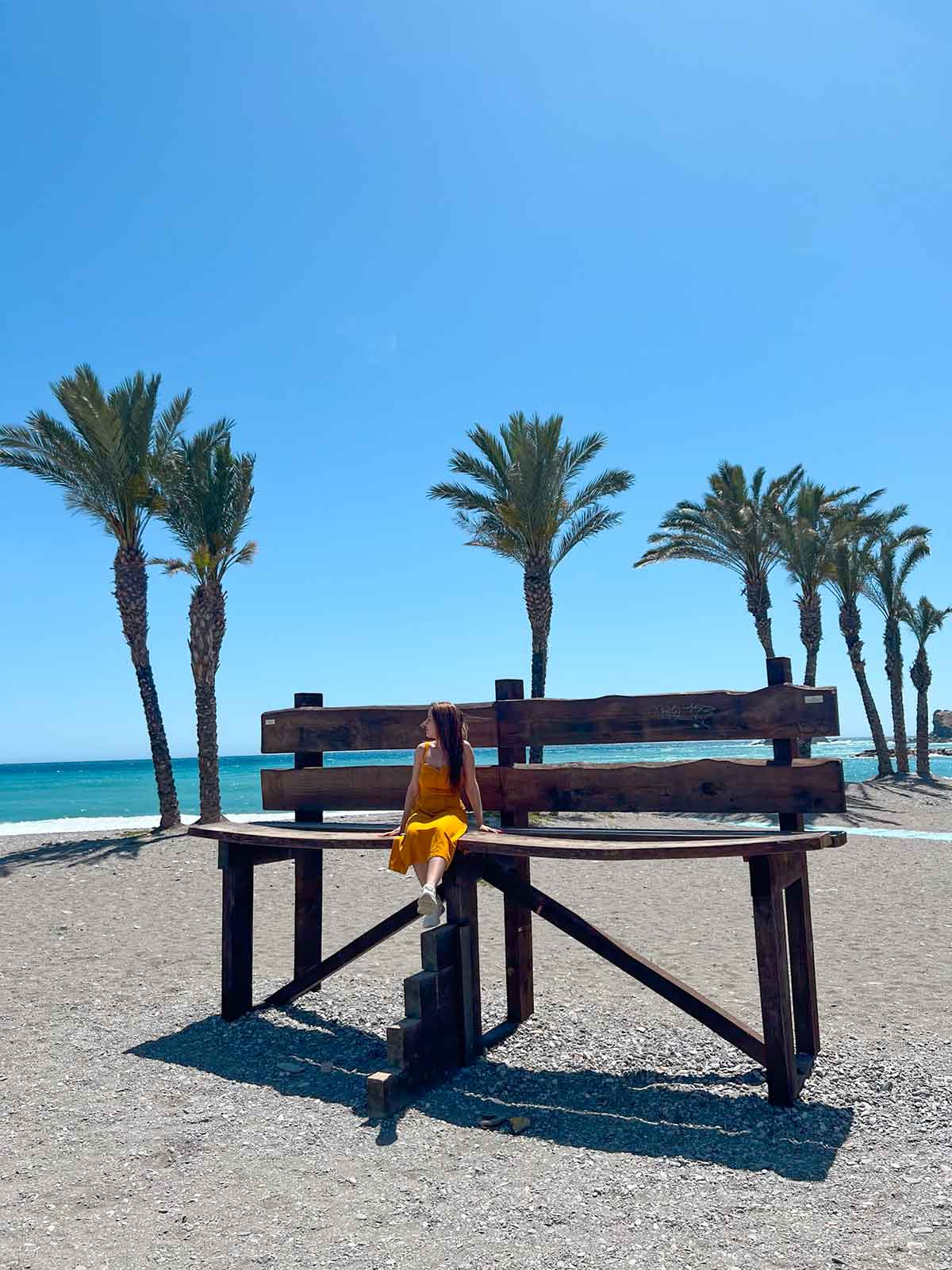 Cristina sat in a wooden giant bench in Costa Tropical Beach in Almuñecar.