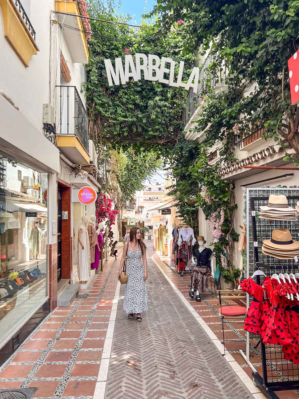 Woman wearing a black and white dress walking down a street in Marbella Old Town.