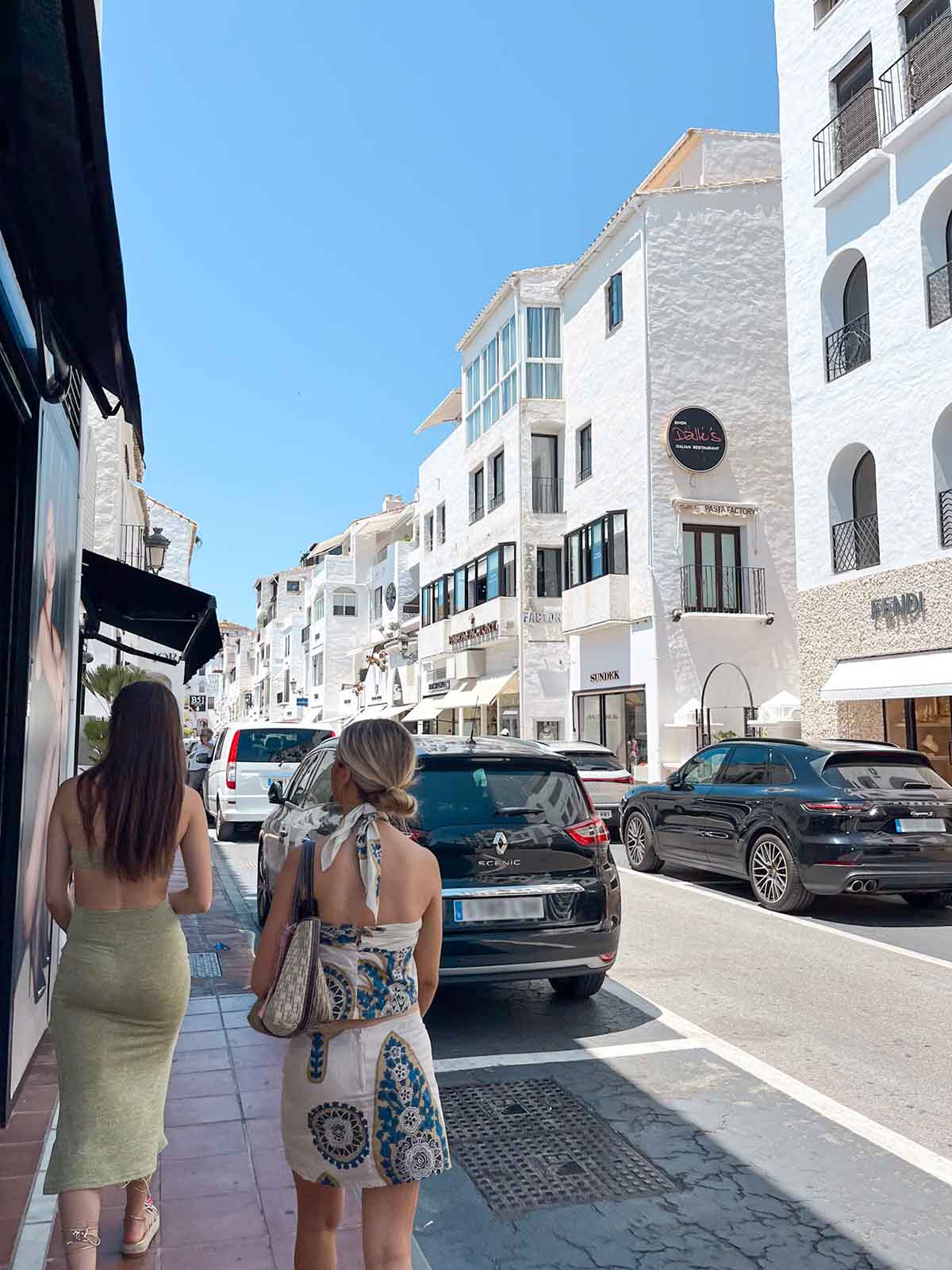 Two women walking down a street in the luxurious port of Puerto Banus, Marbella.