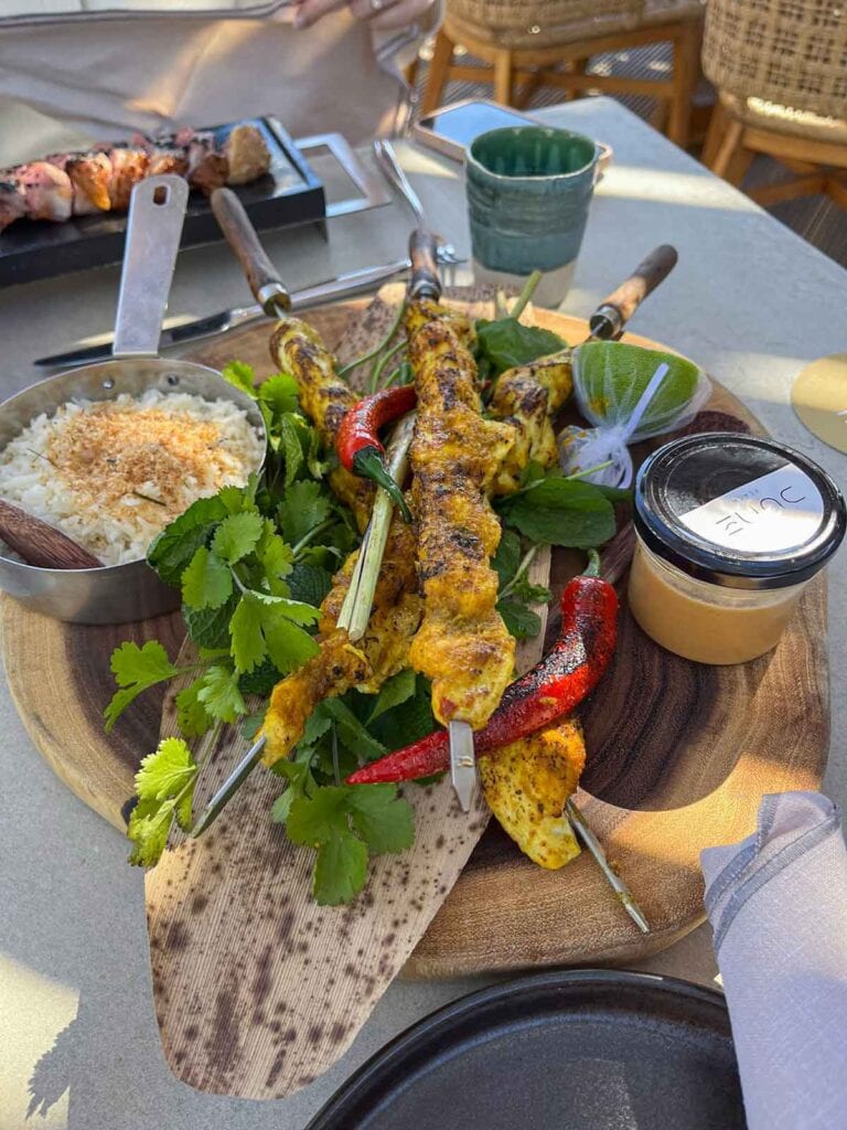 Chicken skewers served with rice and peanut butter sauce.