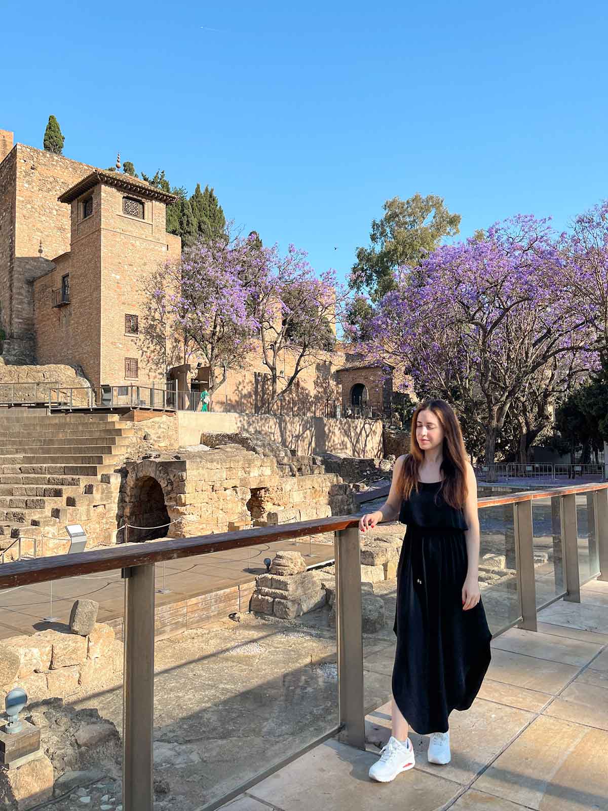 The Ultimate Guide to Exploring Alcazaba de Malaga 9 Woman wearing a long black dress outside the Alcazaba fortress palace in Malaga.