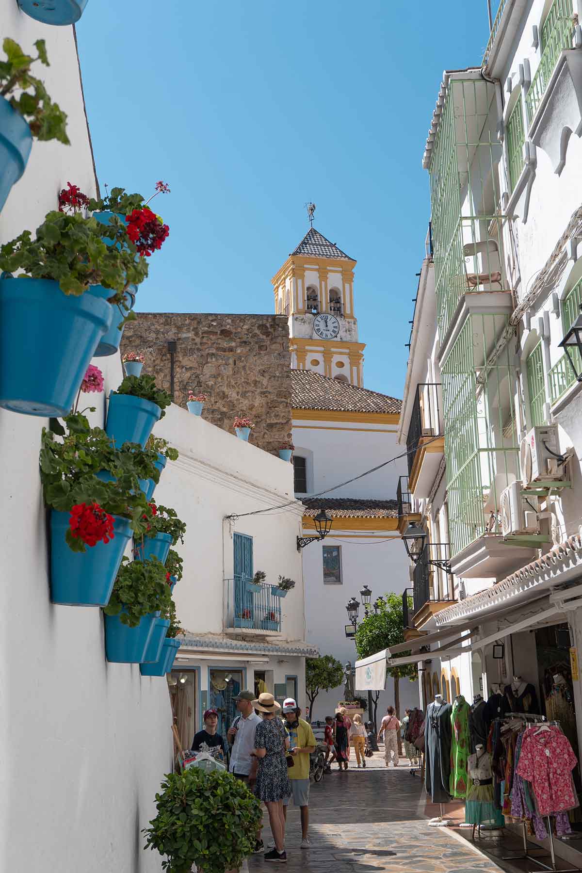 The beautiful view from Calle Carmen, a street with flower pots and the view of a tower church in Marbella.