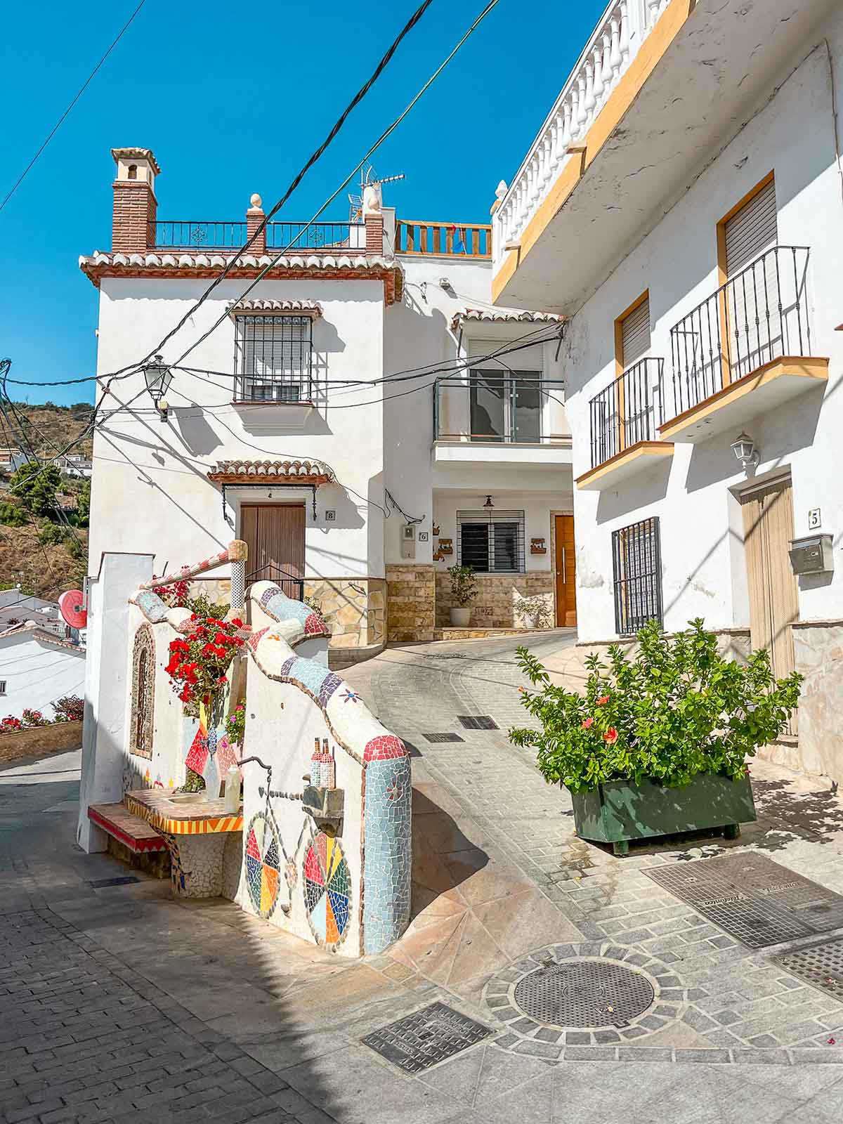 A whitepainted street with a mosaic mural in the town of Moclinejo, Malaga.