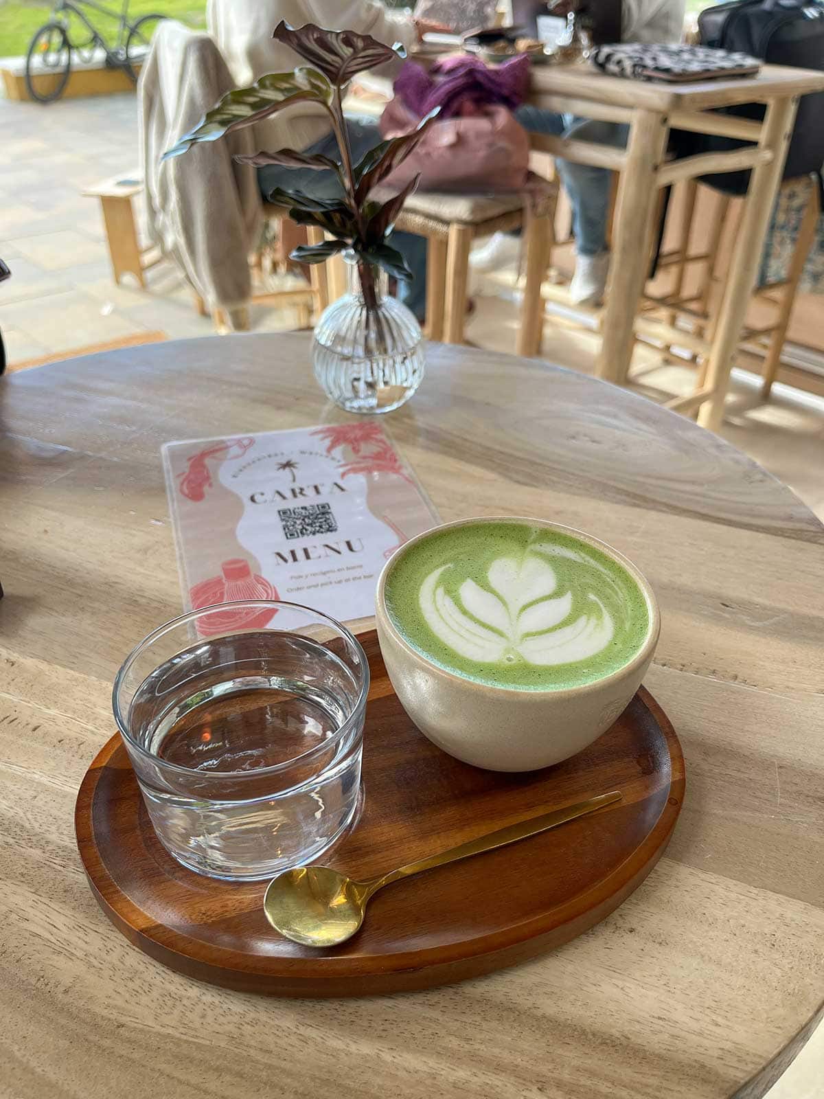 Matcha latte next to a glass of water in a wooden tray at Brisa Specialty Coffee in Rincon de la Victoria.