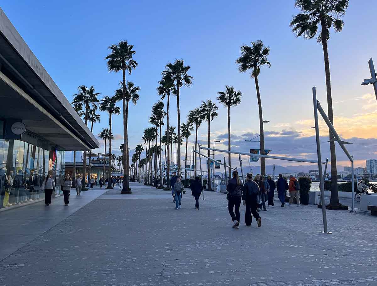 People walking in Muelle Uno at sunset.