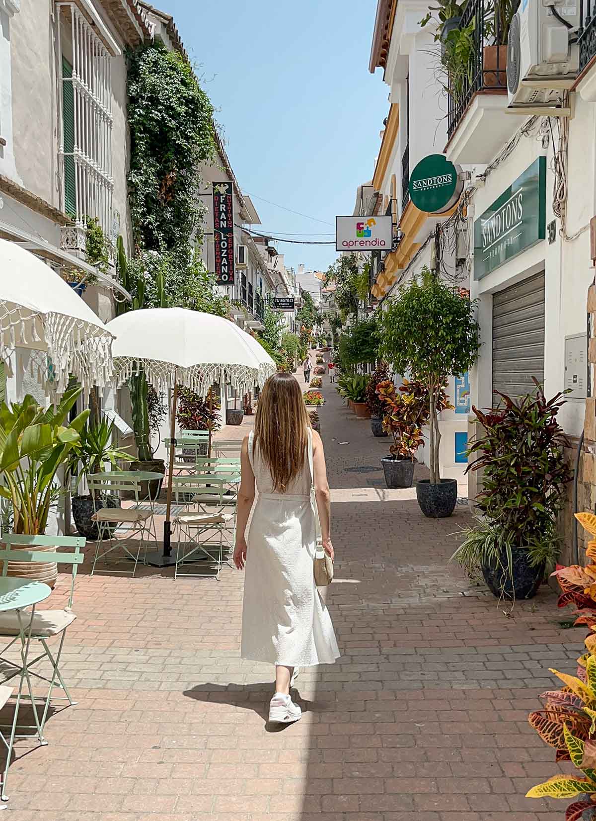 Where to Eat in Estepona (My Top Recommendations) 2 Cristina walking down a pretty street with cafes and shops in Estepona old town, Malaga, Spain.