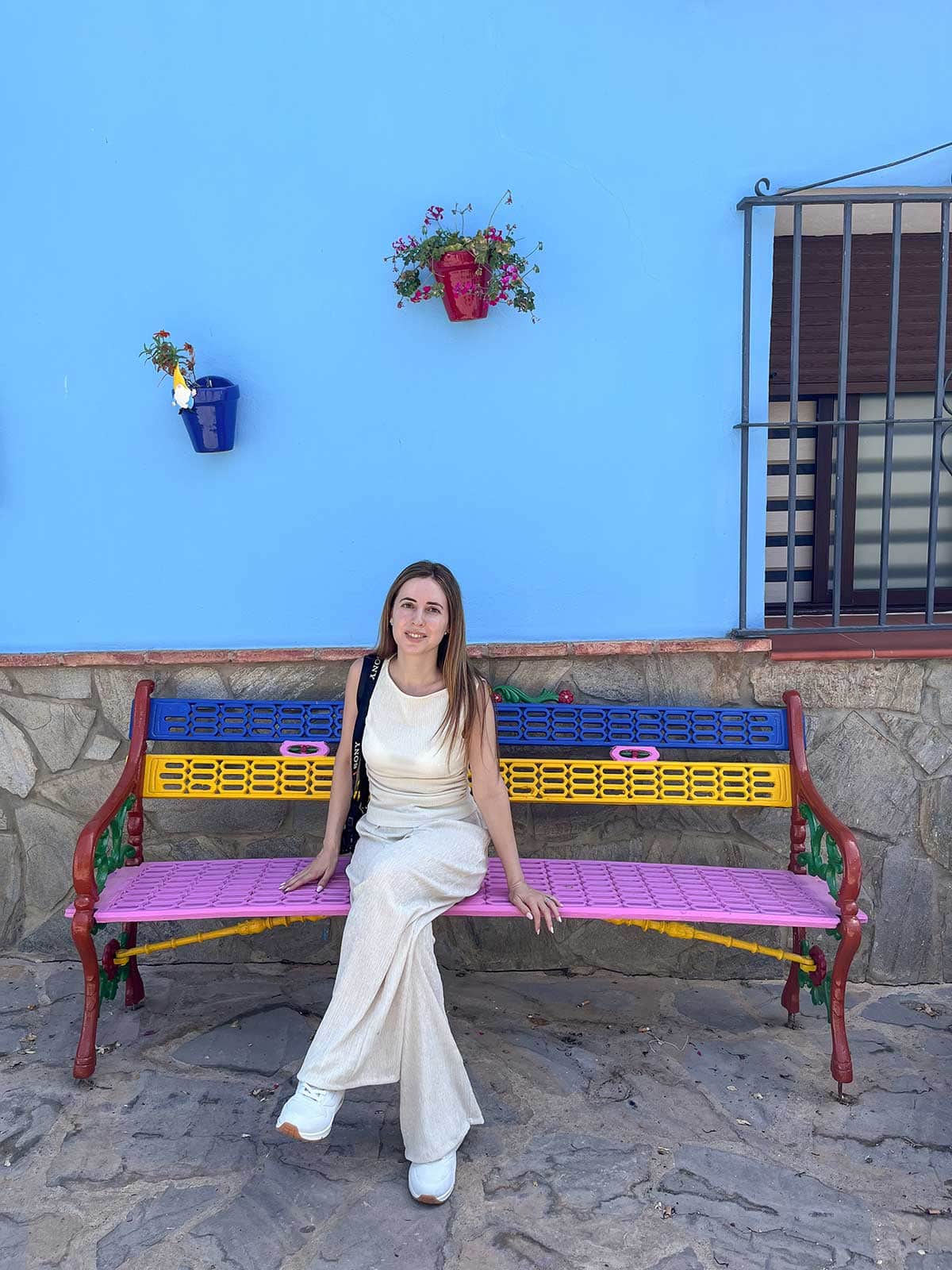 Things to Do in Juzcar, The Blue Village in Malaga 21 Cristina sat in a colourful bench in Juzcar, the blue village, Malaga.