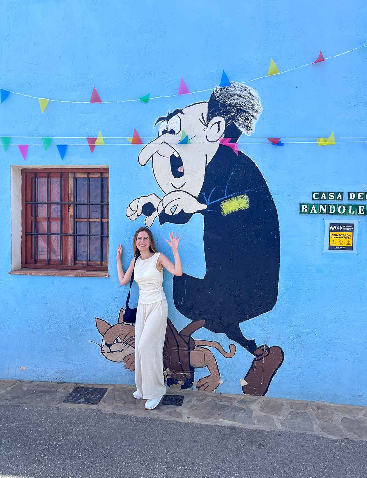Things to Do in Juzcar, The Blue Village in Malaga 7 Cristina posing in front of Gargamel painting in Juzcar, Malaga, Spain.