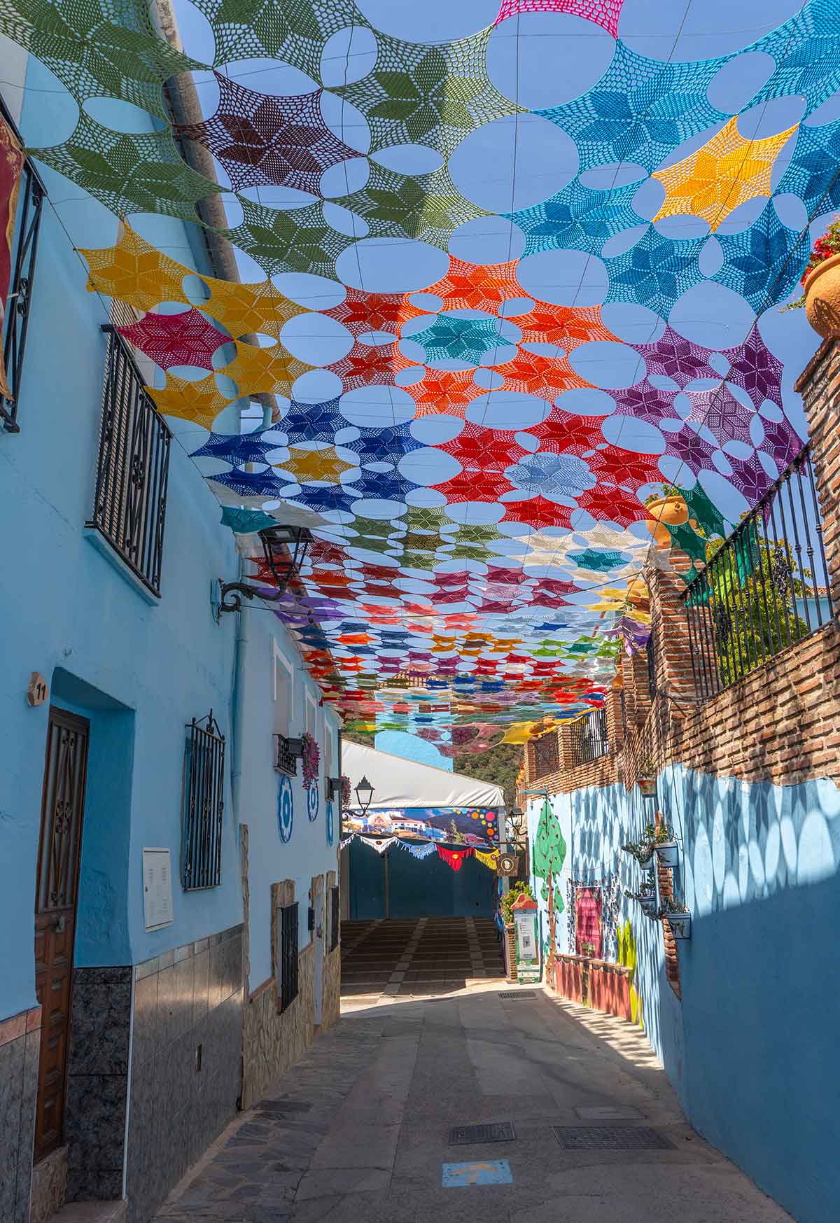 Things to Do in Juzcar, The Blue Village in Malaga 16 Colourful sunshade in the street leading to Juzcar church.