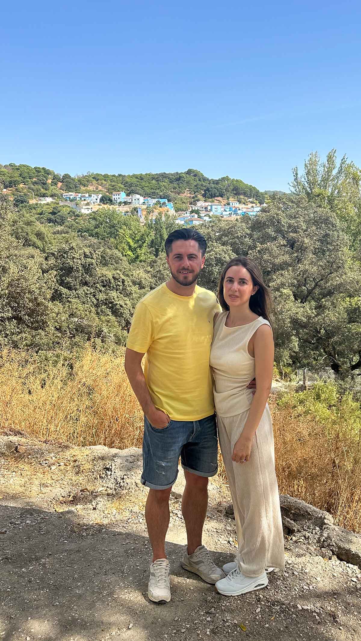 Things to Do in Juzcar, The Blue Village in Malaga 18 A couple with the background of a panoramic view of the mountains and Juzcar village in Malaga, Spain.