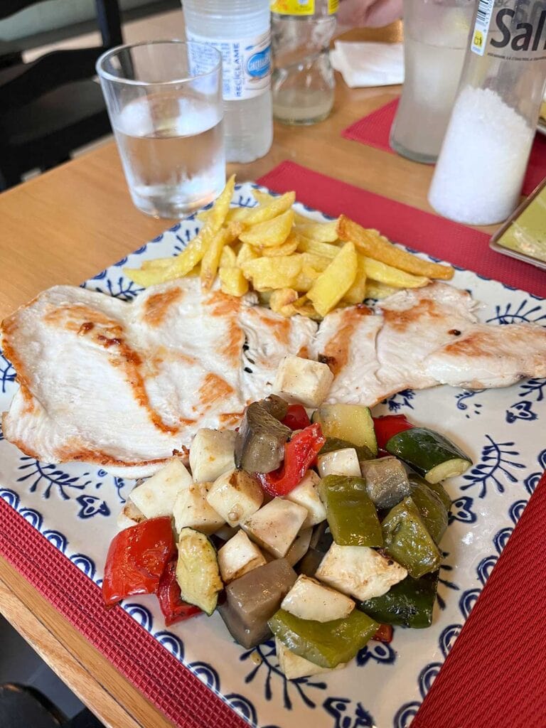 Ultimate Guide to Gluten-Free Seville 13 Grilled chicken with vegetables and chips at Postigo 10 restaurant in Seville.